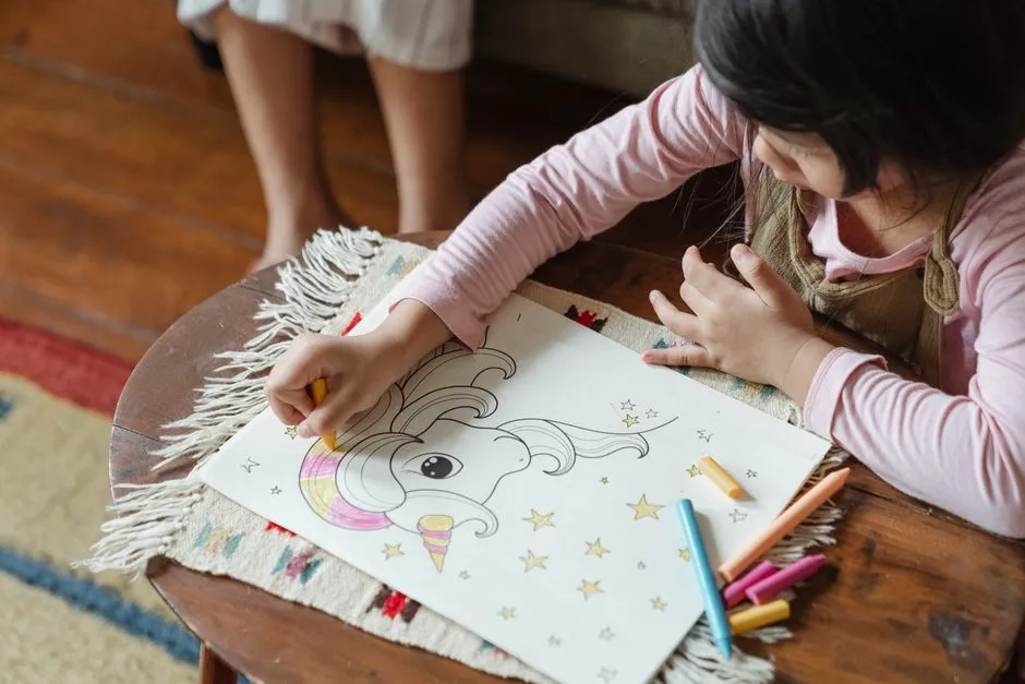 A young child coloring in a coloring book with crayons at a table
